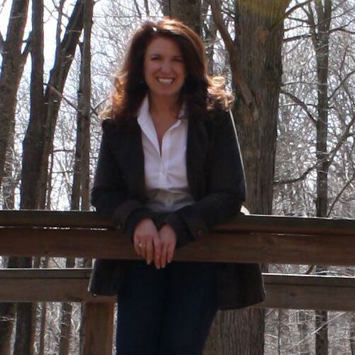 A woman leaning on the railing of a wooden fence.