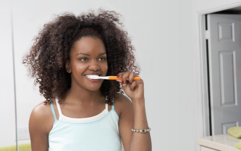 Woman looking in a mirror while brushing her teeth