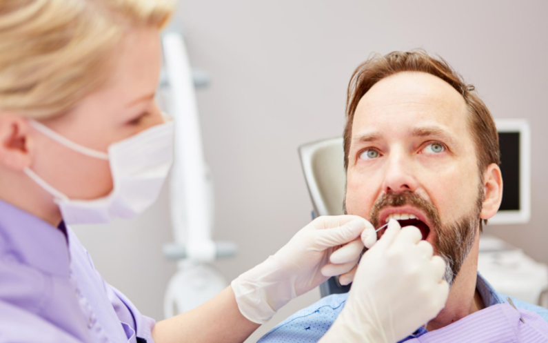 Man at the dentist with the hygienist flossing her teeth.