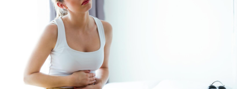 Woman with arms wrapped around her stomach suffering from leaky gut