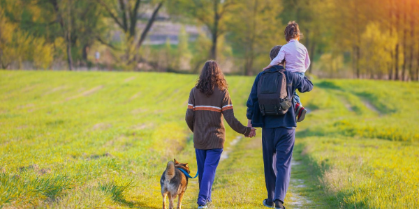 Family walking through a field with their dog