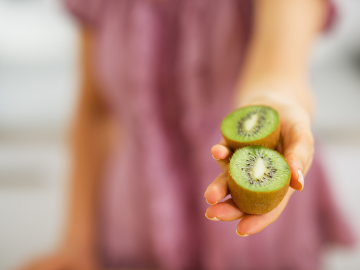 Hand holding a cut kiwi fruit