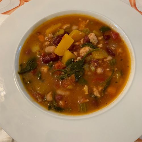 A bowl of soup with beans and greens.