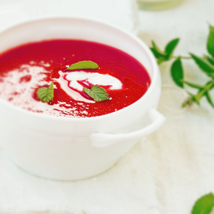 A bowl of soup with fresh herbs on the side.