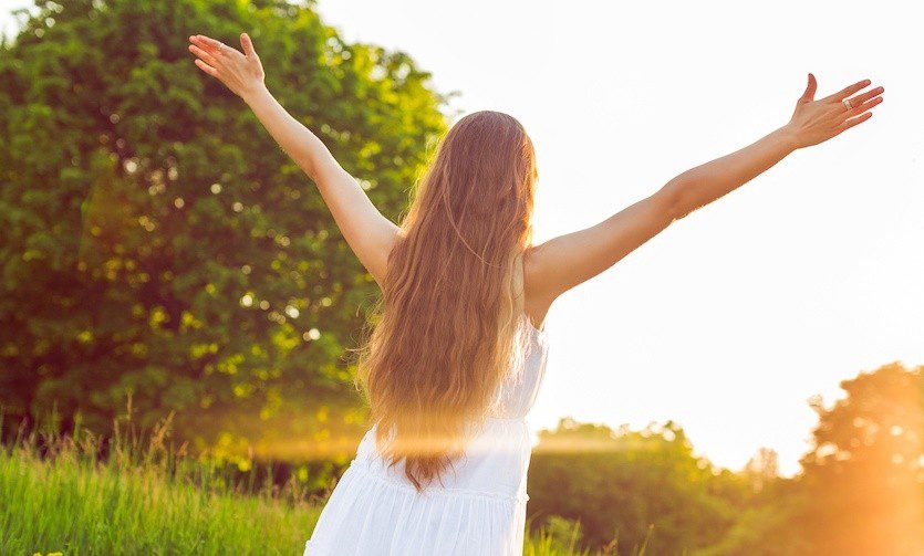 A woman with long hair is standing in the grass.