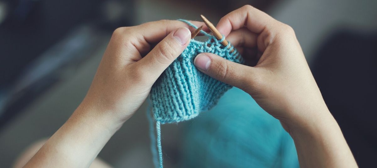 A person knitting something with wooden needles.