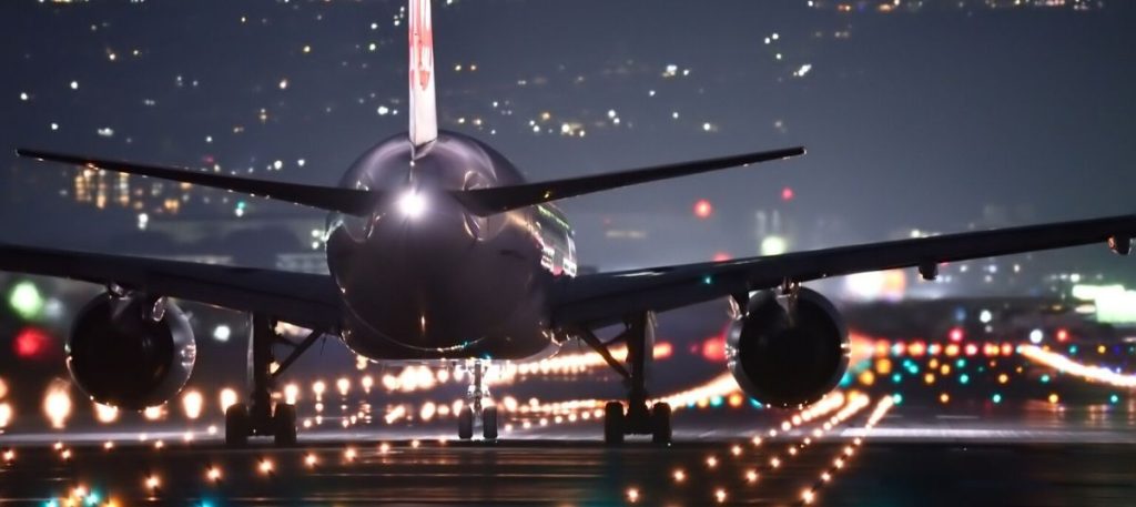 A large airplane is on the runway at night.