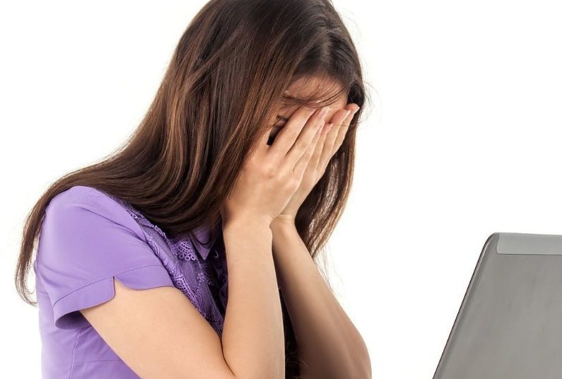 A woman covering her face with her hands.