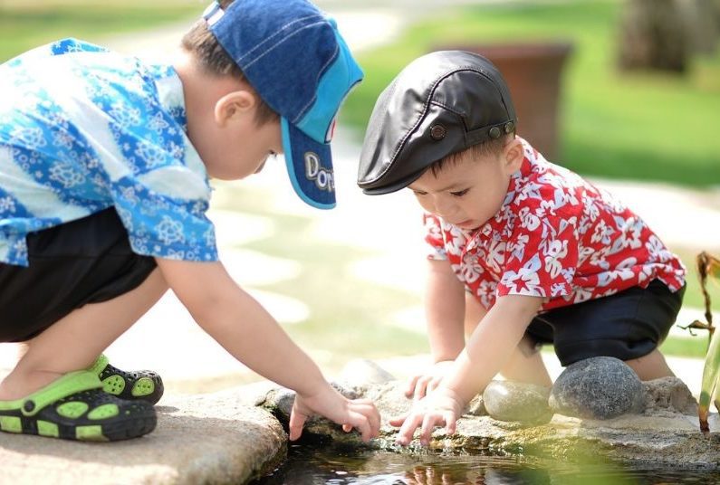 Two young boys playing with a toy in water.