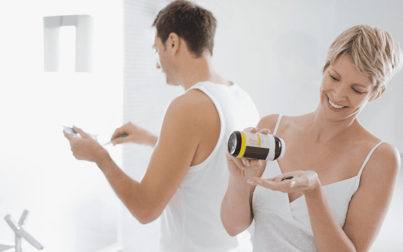 A man and woman holding jars of pills.