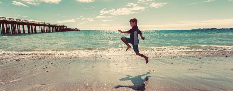 A boy jumping in the air on the beach