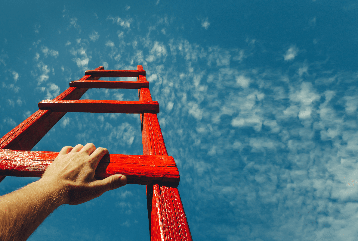 A hand reaching up to reach the top of a ladder.