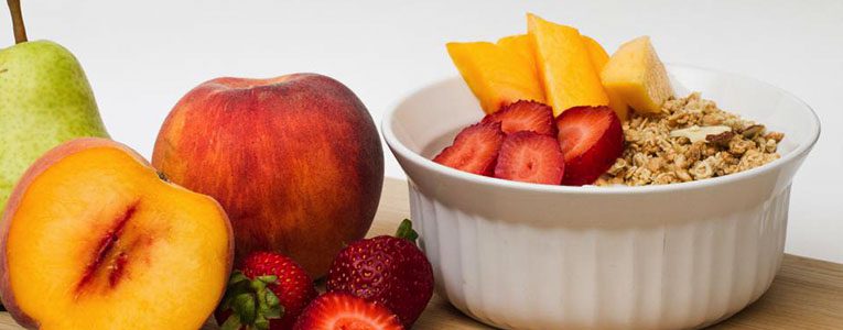 A bowl of fruit and an apple on the table.