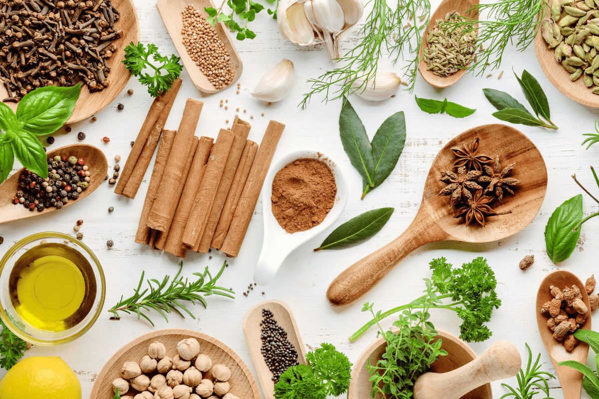 A table topped with spices and herbs on top of a white surface.