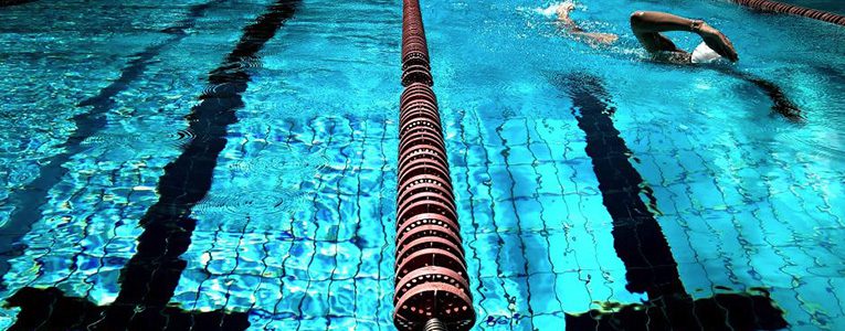 A person swimming in the pool with a long pole.