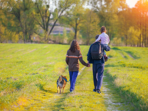 A woman and child walking with a dog on a path.