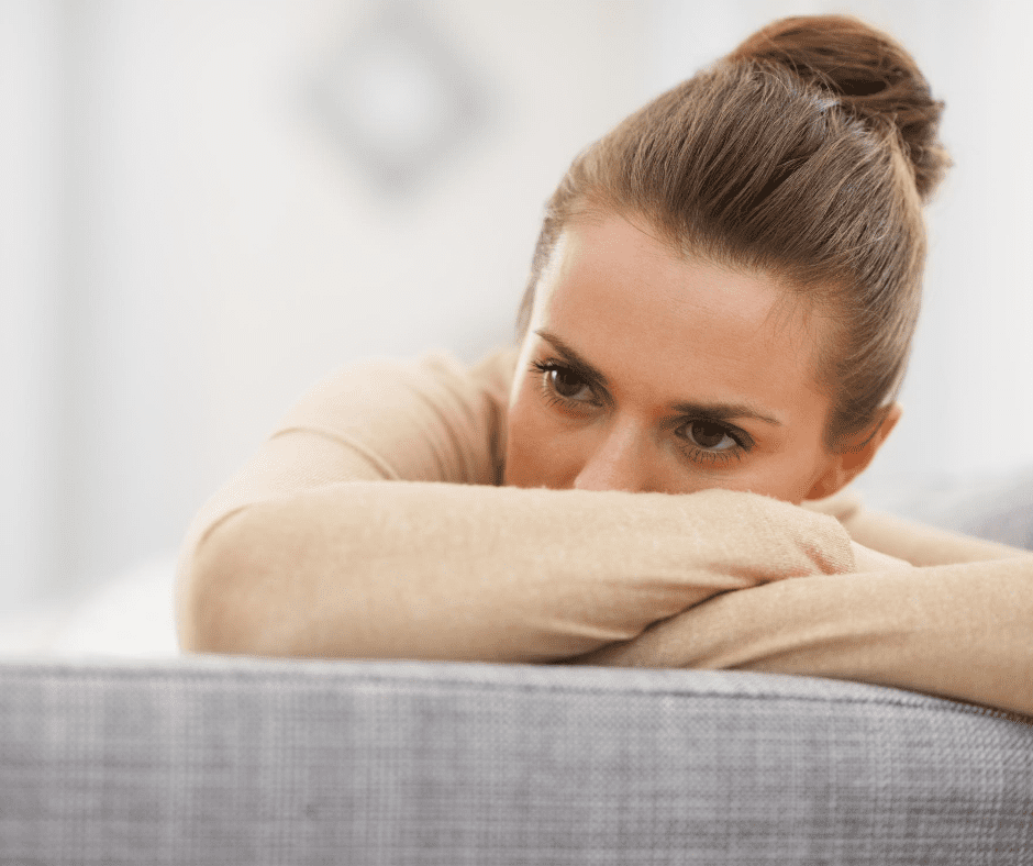 A woman sitting on top of a couch with her arms crossed.