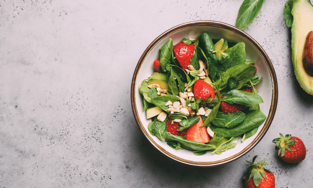 A bowl of salad with strawberries and nuts.