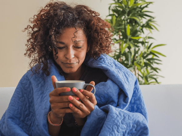 A woman wrapped in a blanket holding a cup.