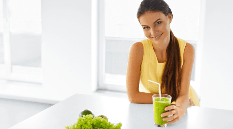 A woman sitting at the table with a glass of green juice.