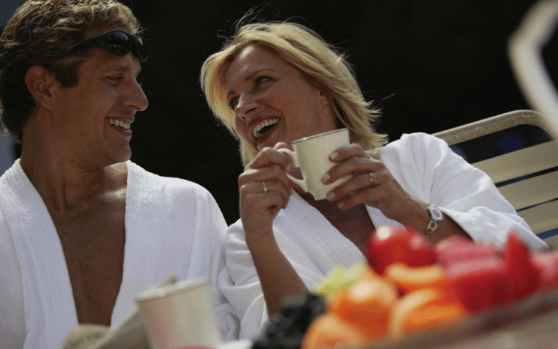 A man and woman sitting at a table with cups.