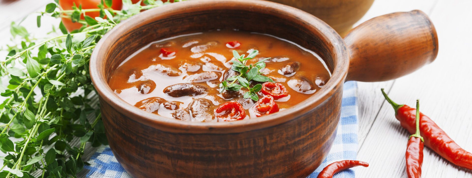 A bowl of soup with mushrooms and peppers.