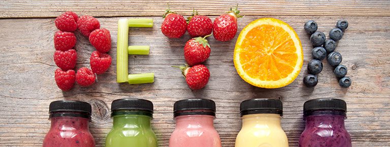 A wooden table topped with fruits and smoothies.