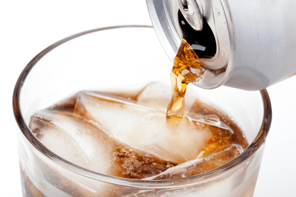 A soda can being poured into ice cubes.