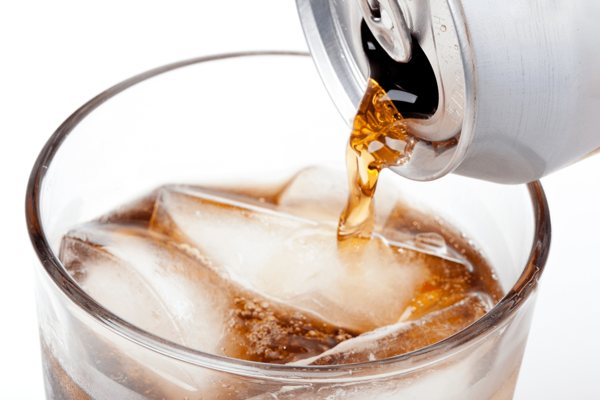 A soda can being poured into ice cubes.