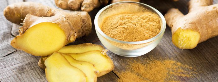 A bowl of ground ginger next to sliced bananas.