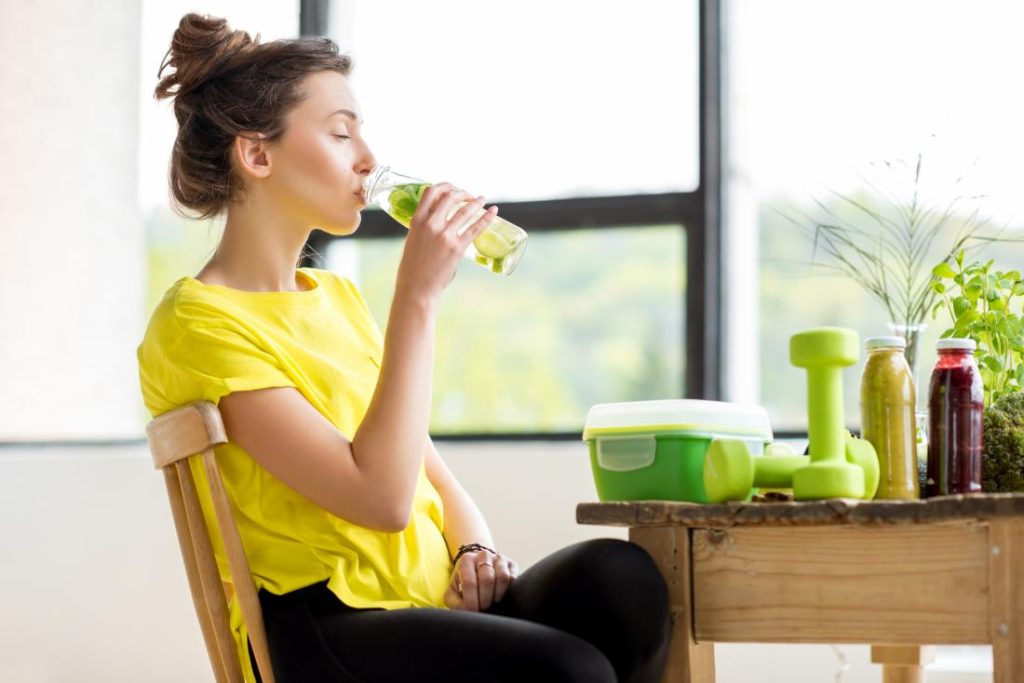 A woman sitting at a table drinking from a cup.