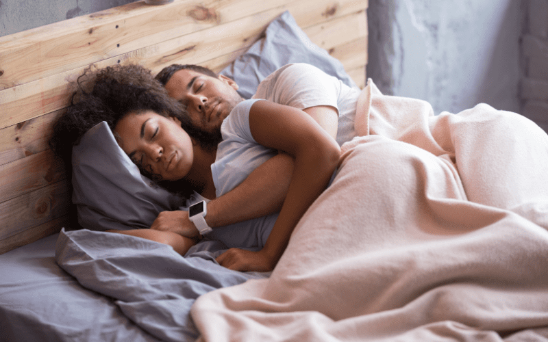 A man and woman sleeping in bed together.