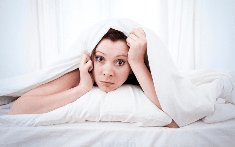 A woman is laying in bed under the covers